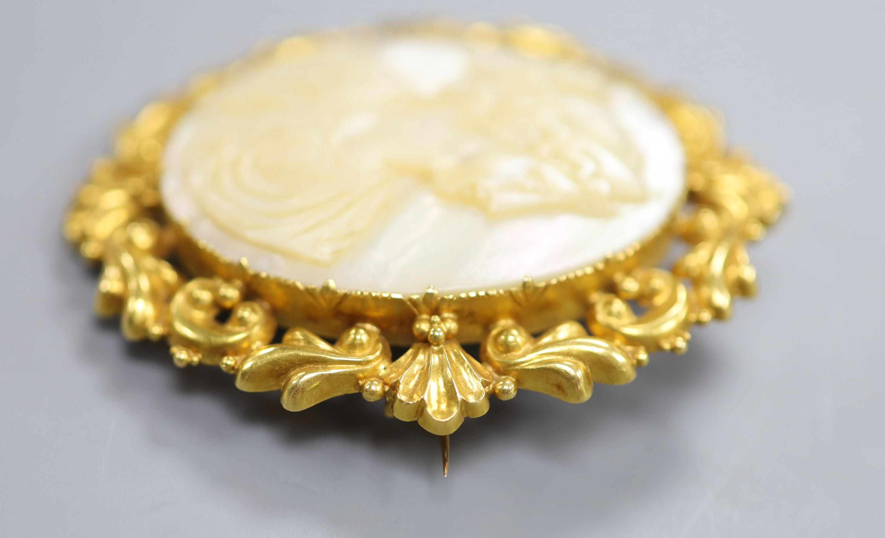 A yellow metal mounted carved mother of pearl cameo oval brooch, 59mm, gross 27.8 grams.